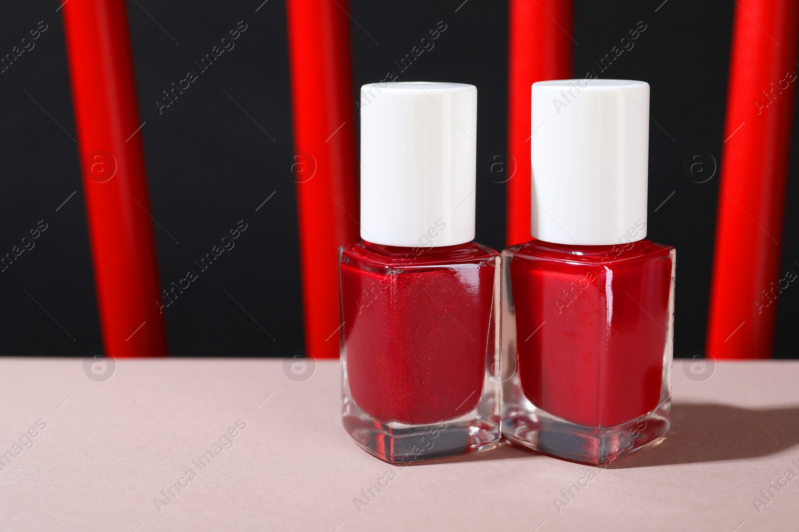 Photo of Red nail polishes in bottles on white table, closeup. Space for text