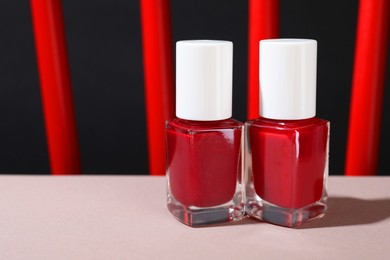 Photo of Red nail polishes in bottles on white table, closeup. Space for text