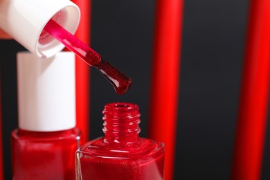 Photo of Red nail polishes in bottles on blurred background, closeup. Space for text