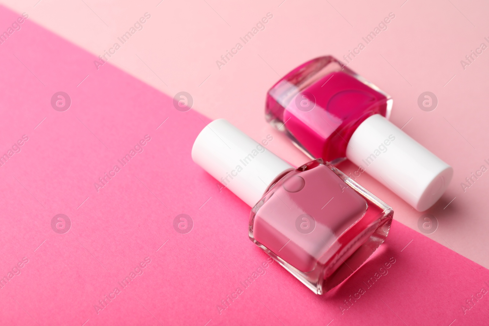 Photo of Nail polishes in bottles on color background, closeup. Space for text