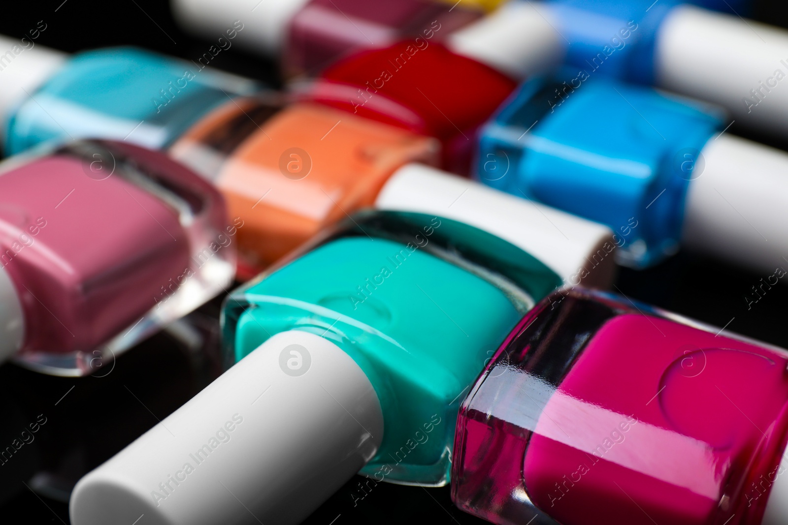 Photo of Set of different nail polishes in bottles on black background, closeup