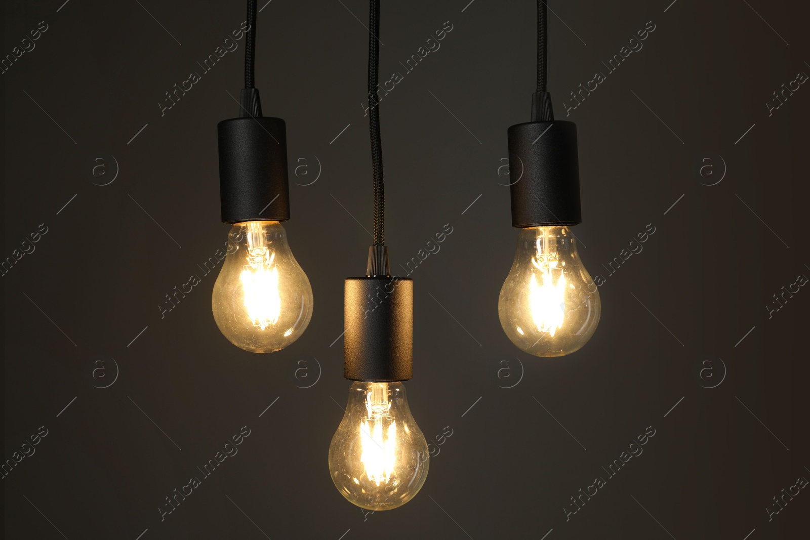 Photo of Light bulbs hanging on cords against grey background