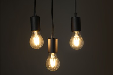 Photo of Light bulbs hanging on cords against grey background