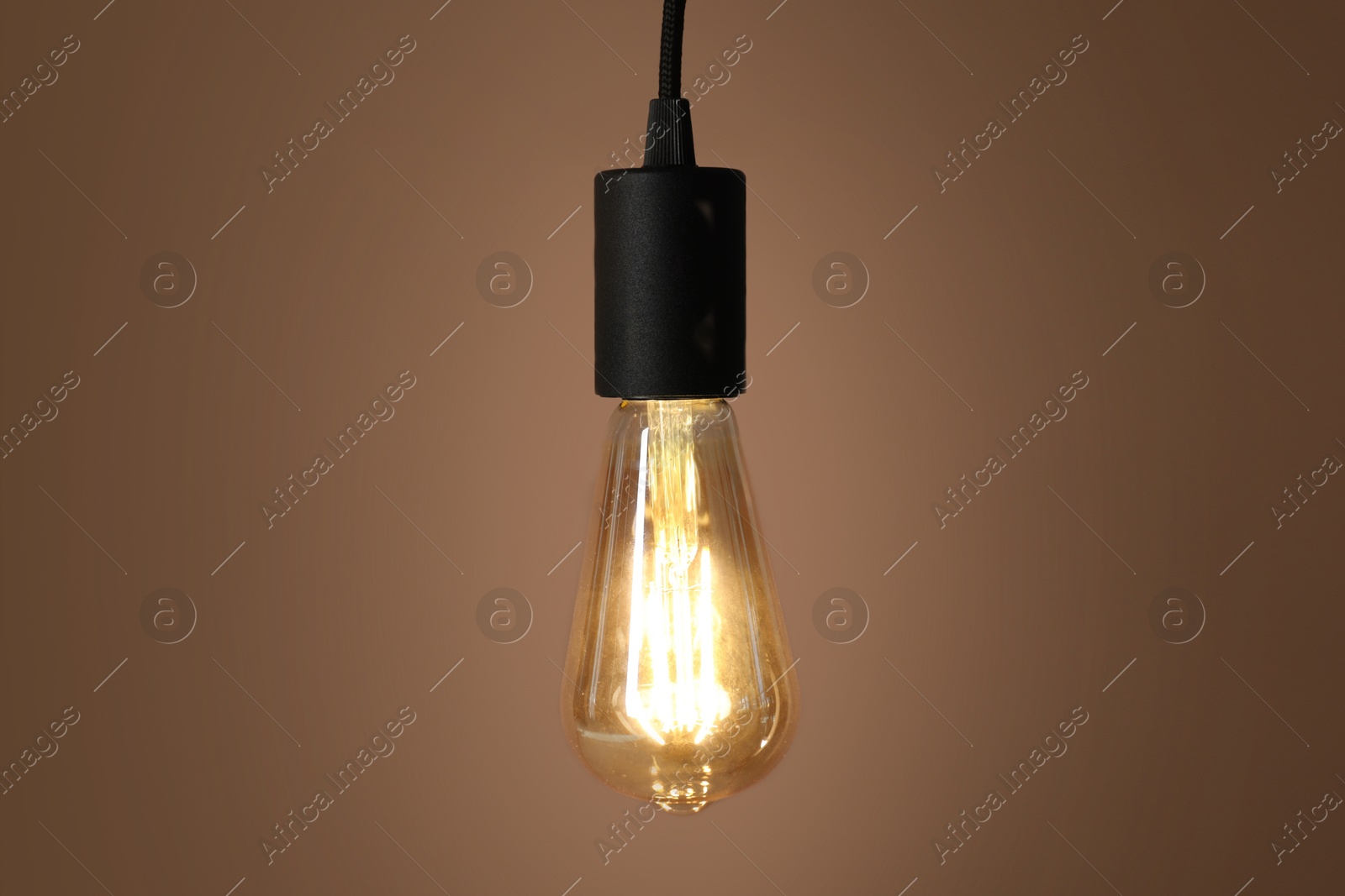 Photo of Light bulb against brown background, space for text