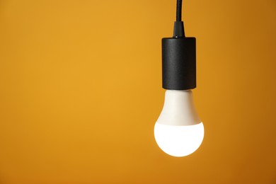 Photo of Light bulb against orange background, space for text