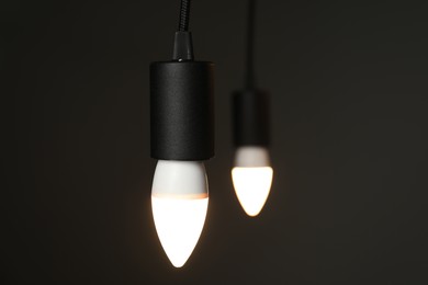 Photo of Light bulbs hanging on cords against grey background, selective focus. Space for text