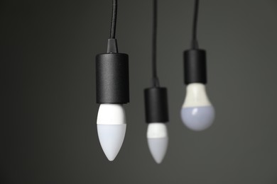 Photo of Light bulbs hanging on cords against grey background, selective focus. Space for text