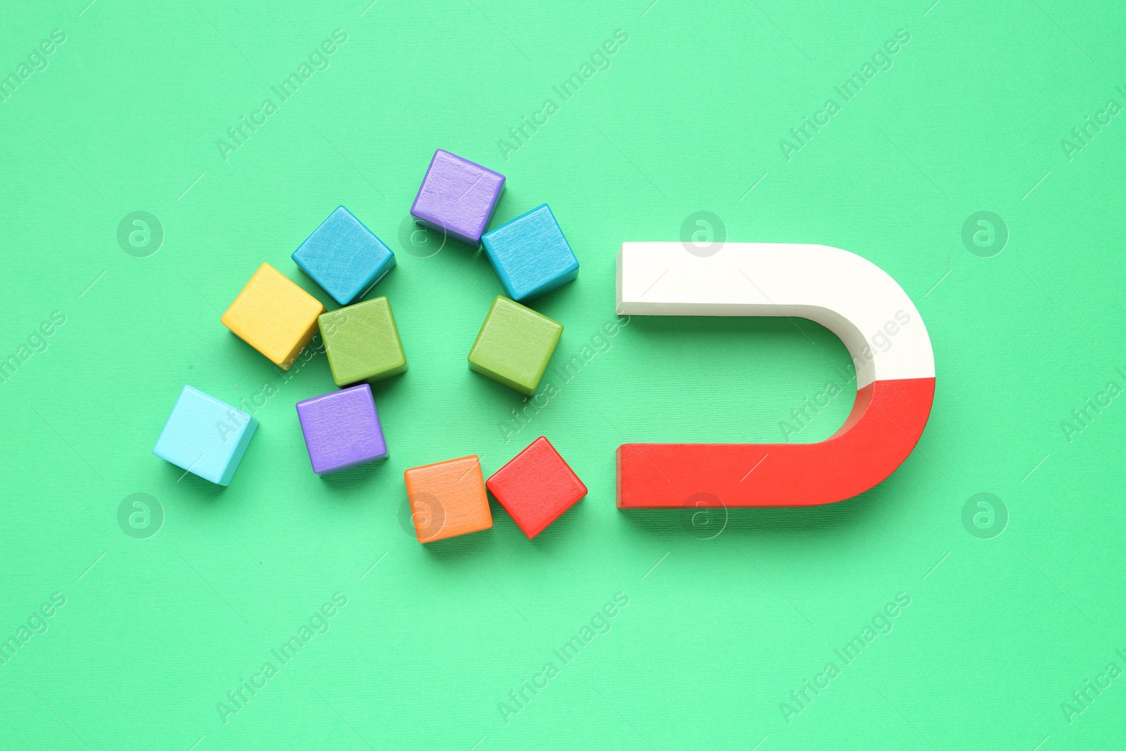 Photo of Magnet attracting colorful cubes on green background, flat lay