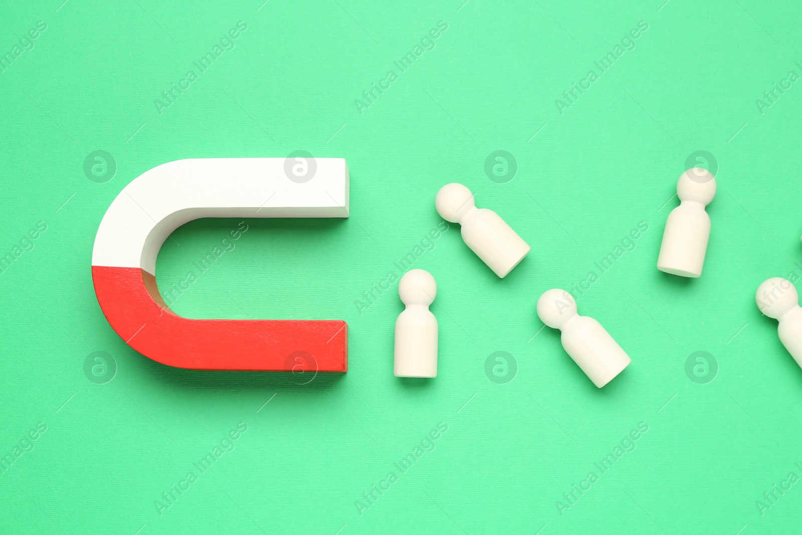 Photo of Magnet attracting human figures on green background, flat lay