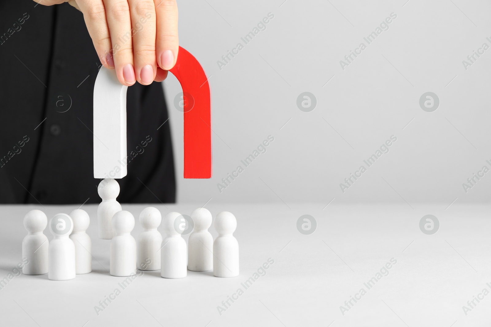 Photo of Woman with magnet attracting piece among wooden ones at white table, closeup. Space for text