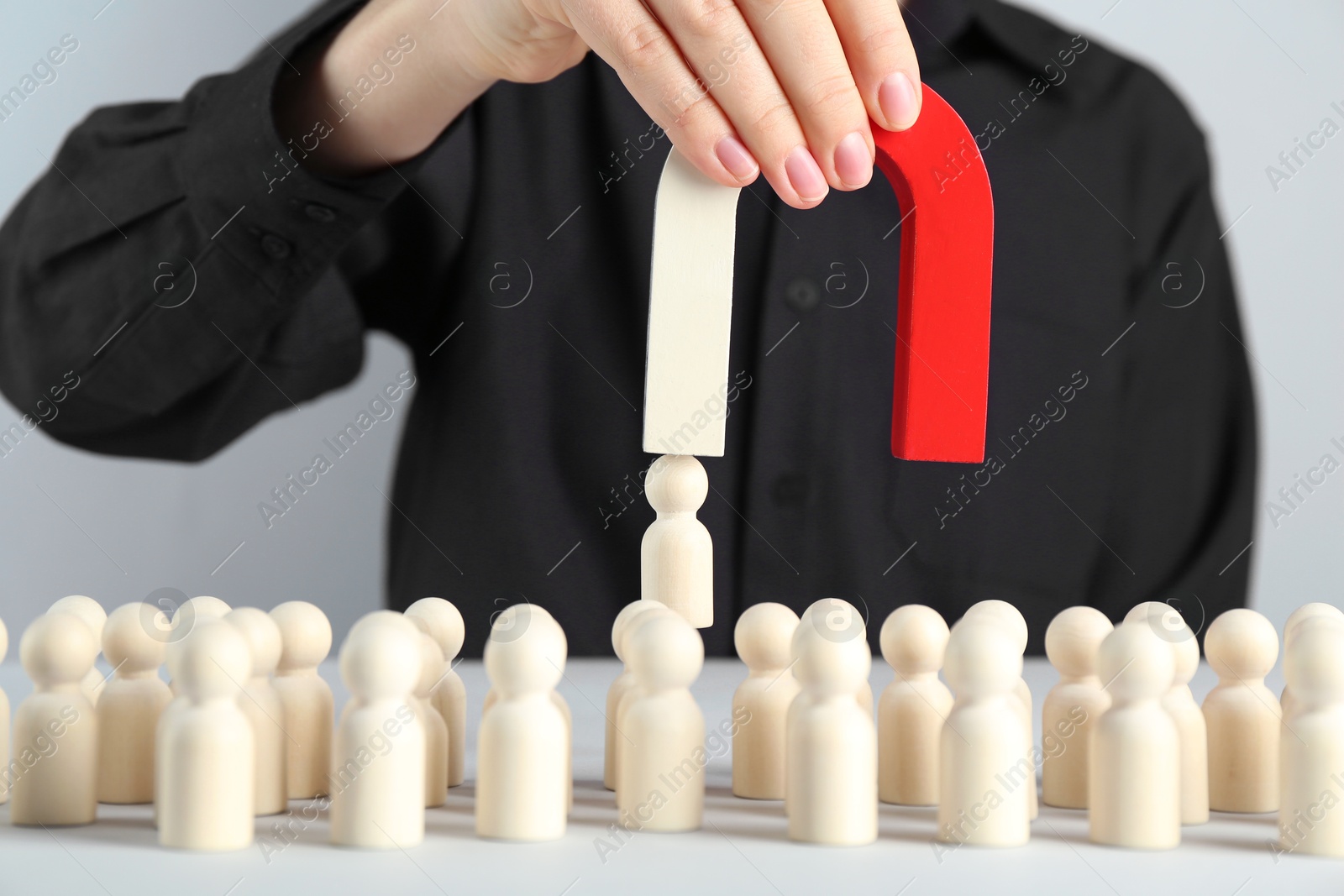 Photo of Woman with magnet attracting piece among wooden ones at white table, closeup