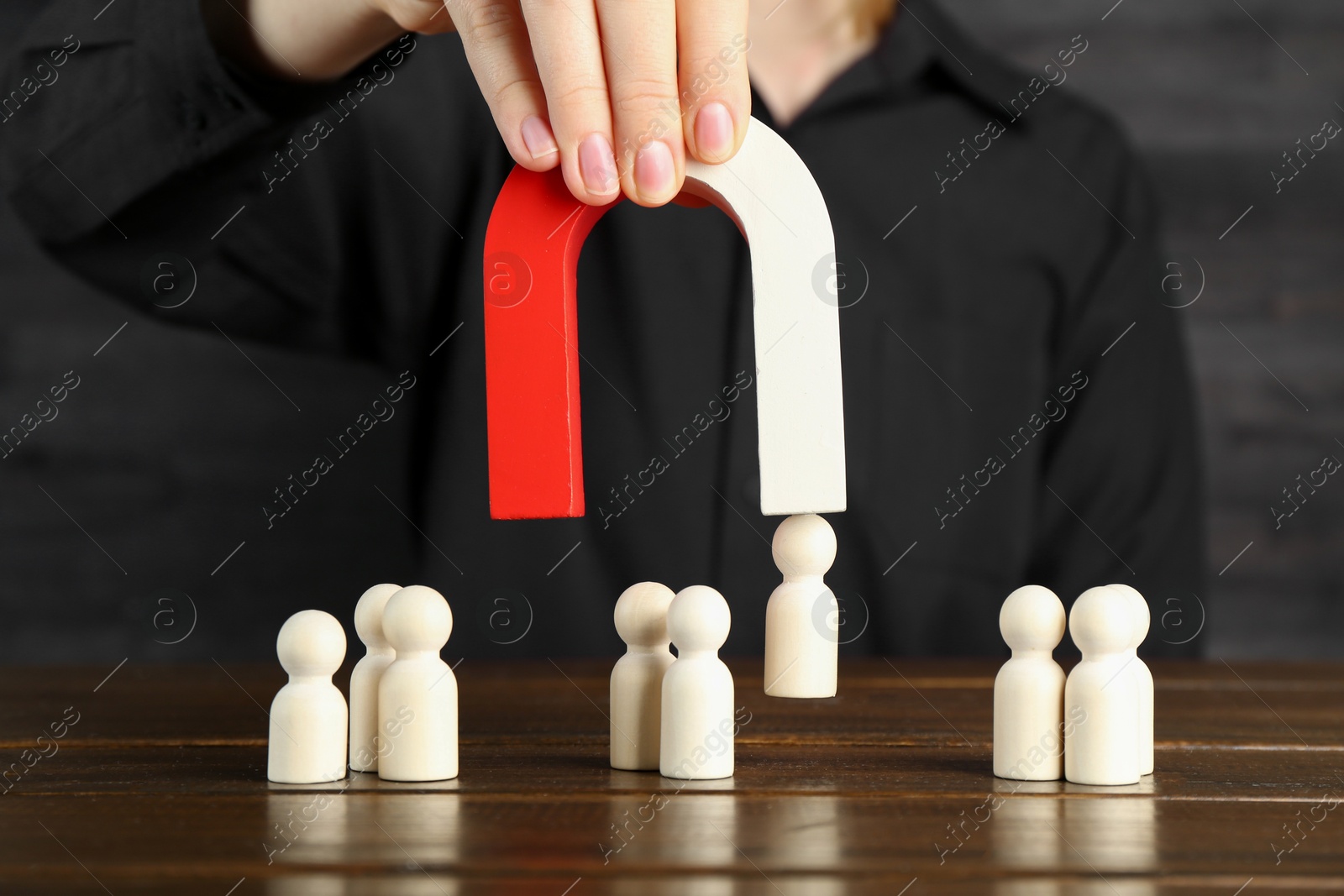 Photo of Woman with magnet attracting piece among wooden ones at table, closeup