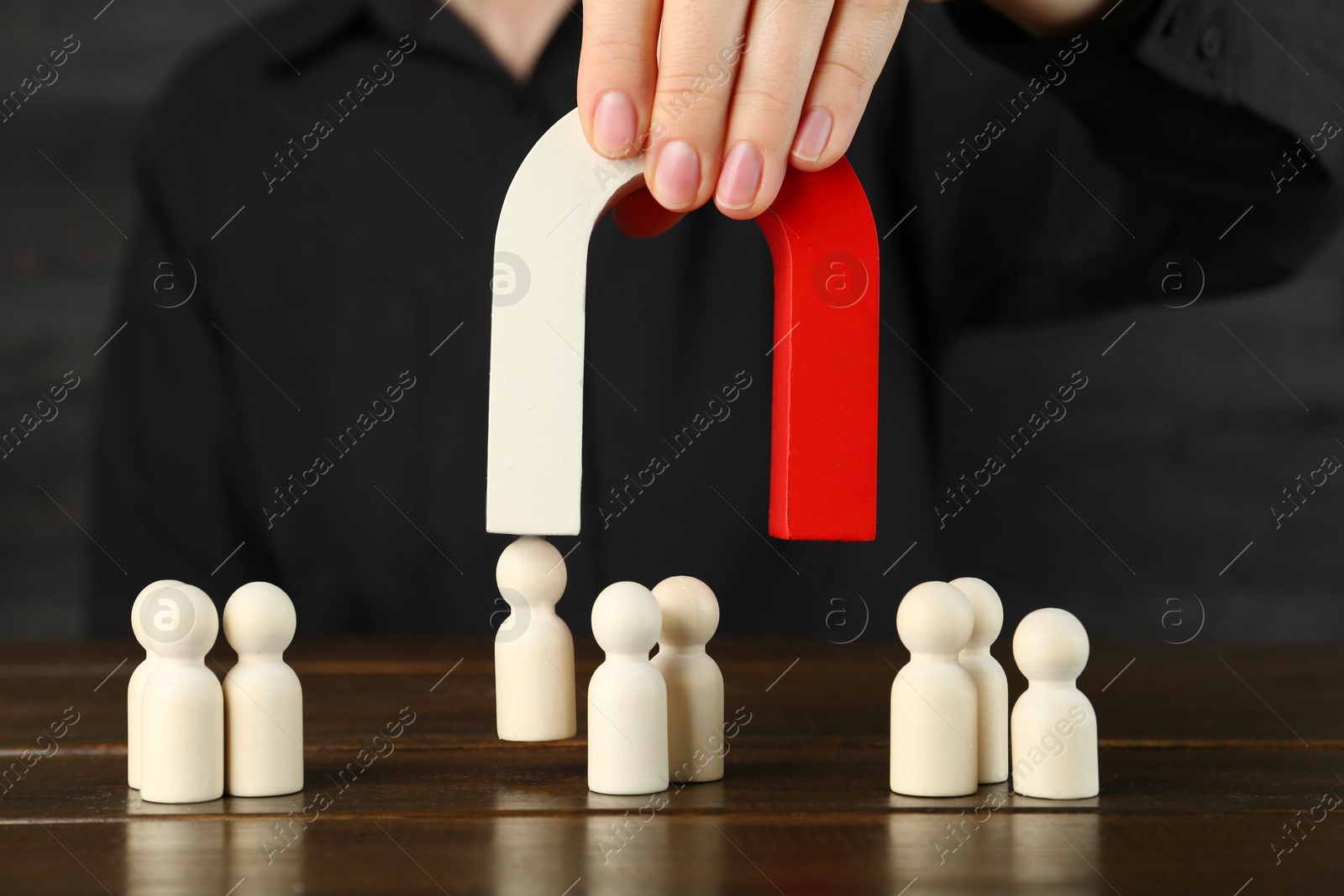 Photo of Woman with magnet attracting piece among wooden ones at table, closeup