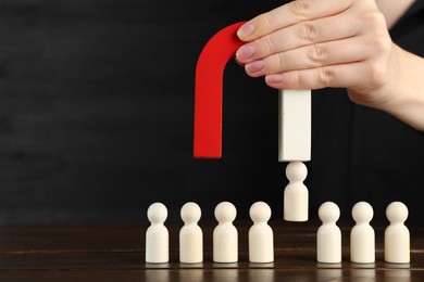 Photo of Woman with magnet attracting piece among wooden ones at table, closeup. Space for text