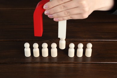 Photo of Woman with magnet attracting piece among wooden ones at table, closeup