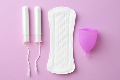 Photo of Menstrual pad, cup and tampons on lilac background, flat lay