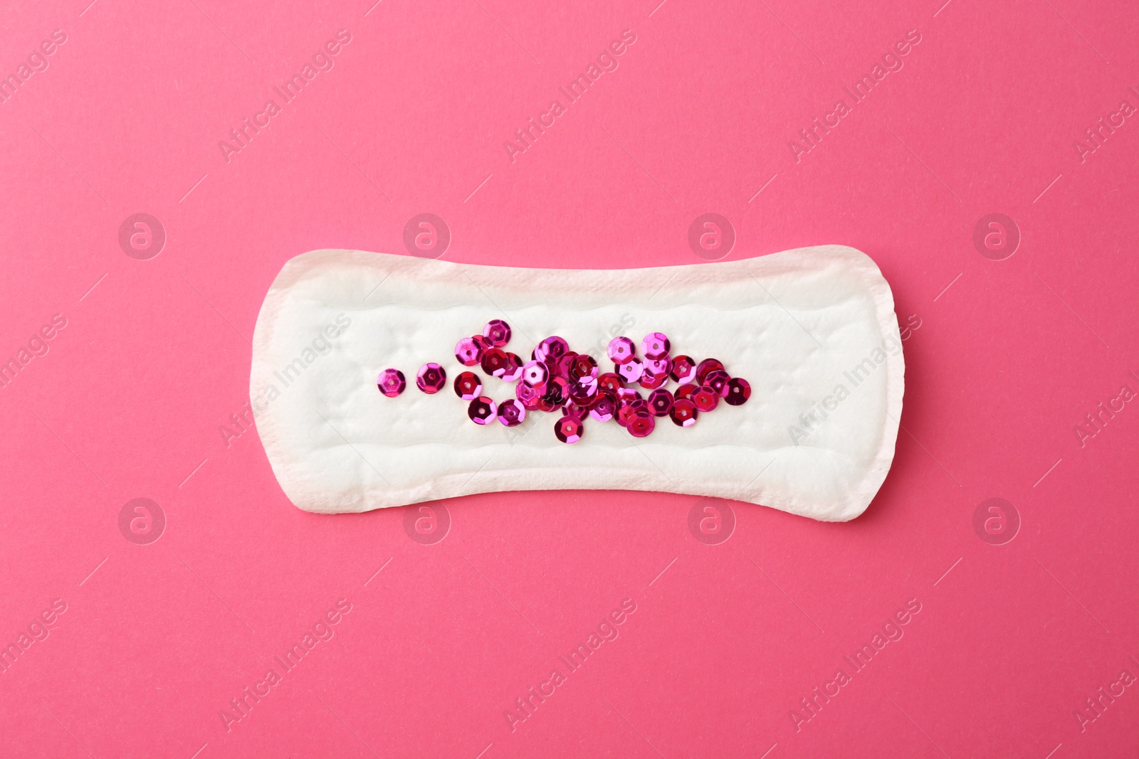 Photo of Menstrual pad with sequins on pink background, top view