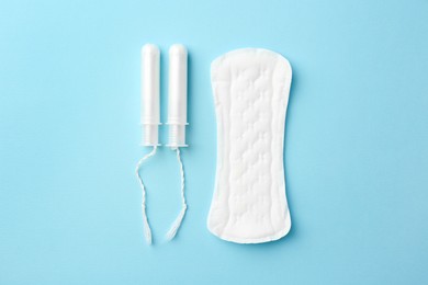 Photo of Menstrual pad and tampons on light blue background, top view