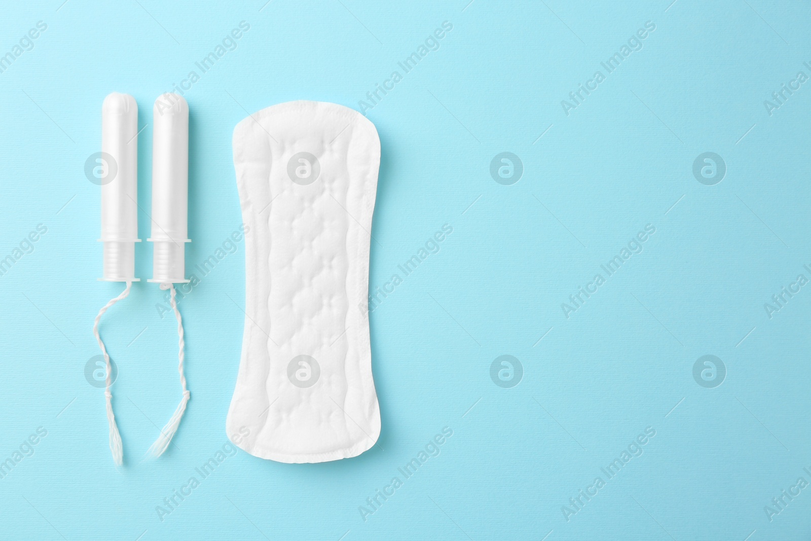 Photo of Menstrual pad and tampons on light blue background, top view. Space for text