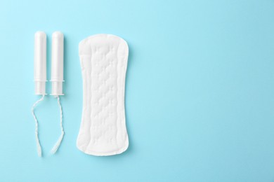 Photo of Menstrual pad and tampons on light blue background, top view. Space for text