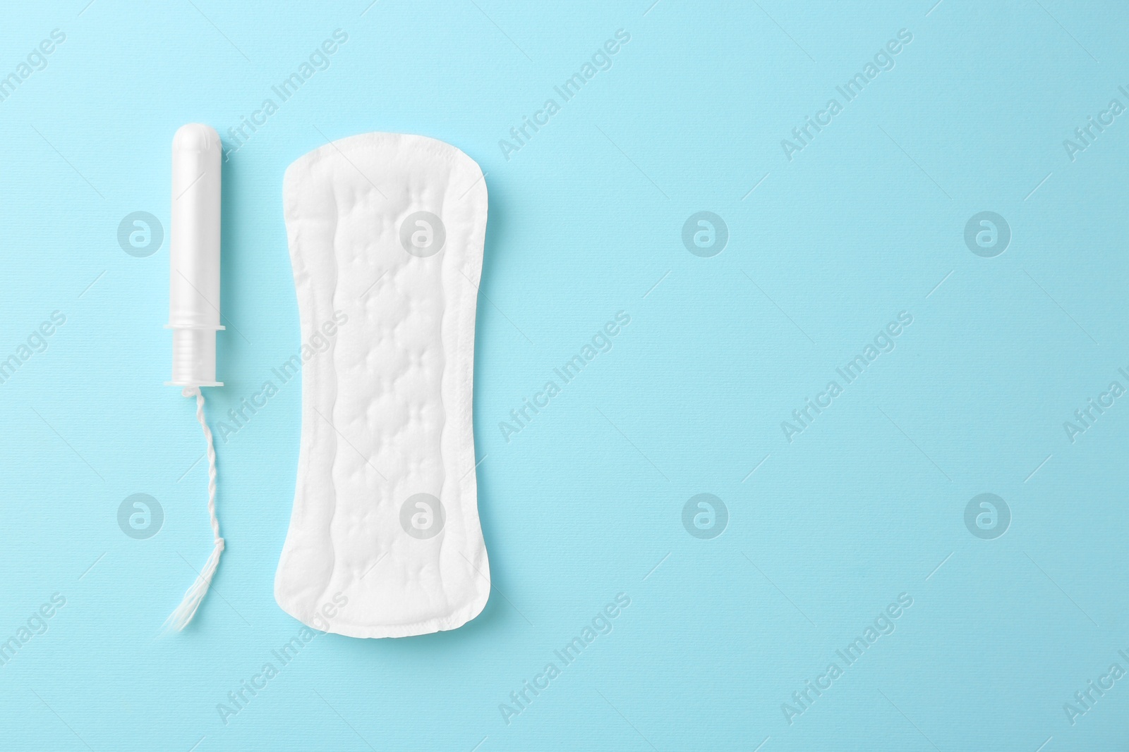 Photo of Menstrual pad and tampon on light blue background, top view. Space for text