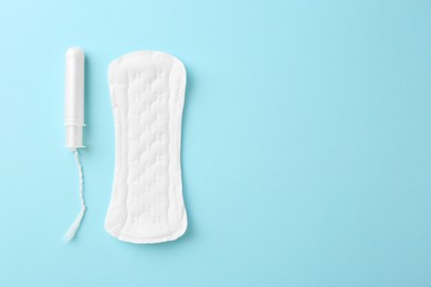 Photo of Menstrual pad and tampon on light blue background, top view. Space for text