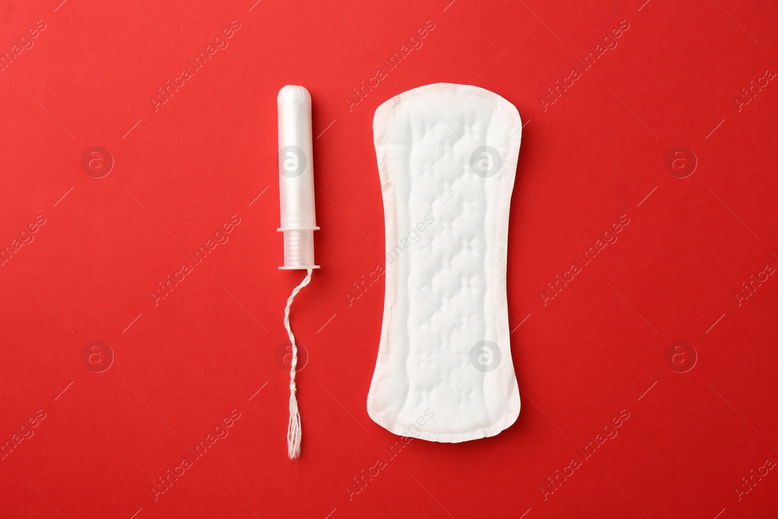 Photo of Menstrual pad and tampon on red background, top view