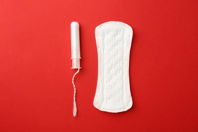 Photo of Menstrual pad and tampon on red background, top view