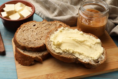 Photo of Fresh bread with butter and peanut paste on blue wooden table, closeup