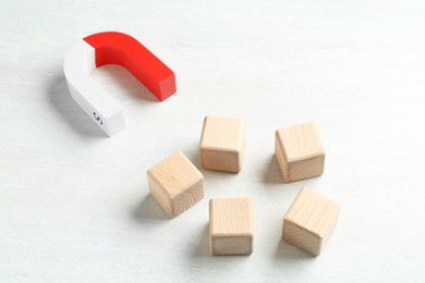 Photo of Magnet attracting wooden cubes on white table