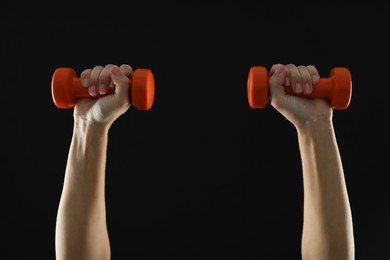 Photo of Woman exercising with dumbbells on black background, closeup