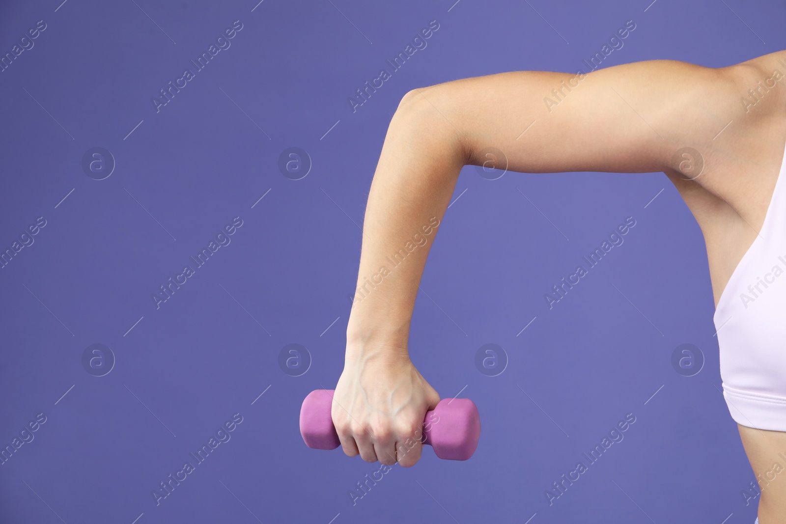 Photo of Woman exercising with dumbbell on purple background, closeup. Space for text