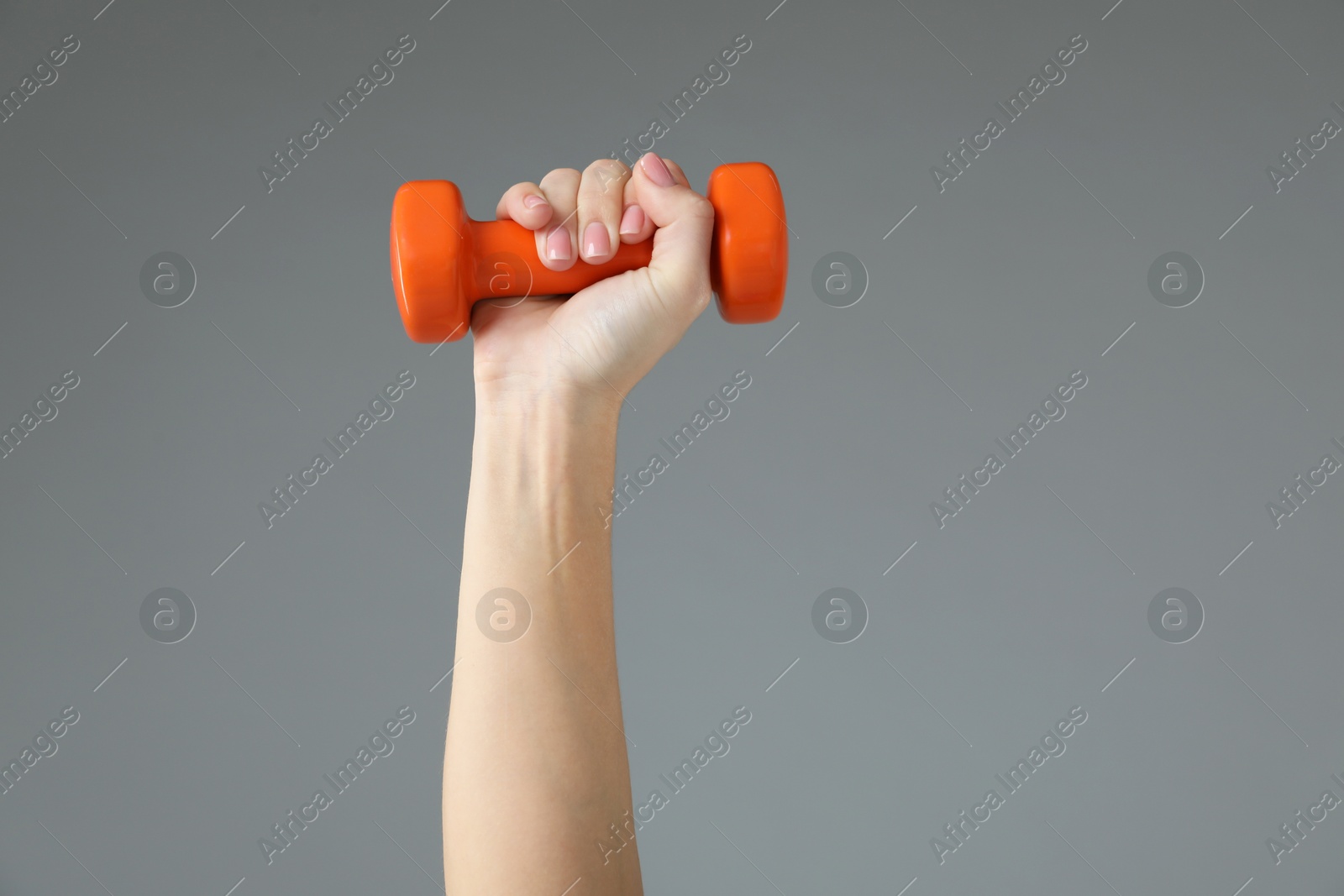 Photo of Woman exercising with dumbbell on light grey background, closeup. Space for text