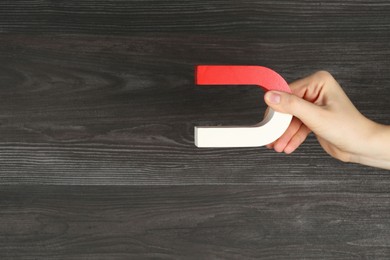 Photo of Woman with horseshoe magnet on wooden background, closeup. Space for text