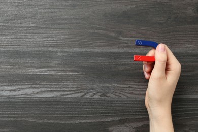 Photo of Woman with horseshoe magnet on wooden background, top view. Space for text