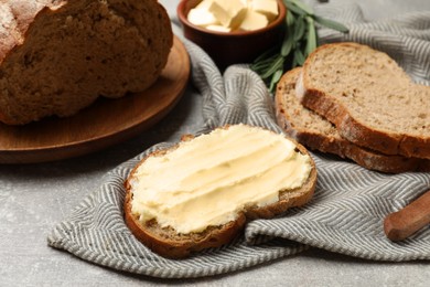 Photo of Fresh bread with butter on grey table, closeup