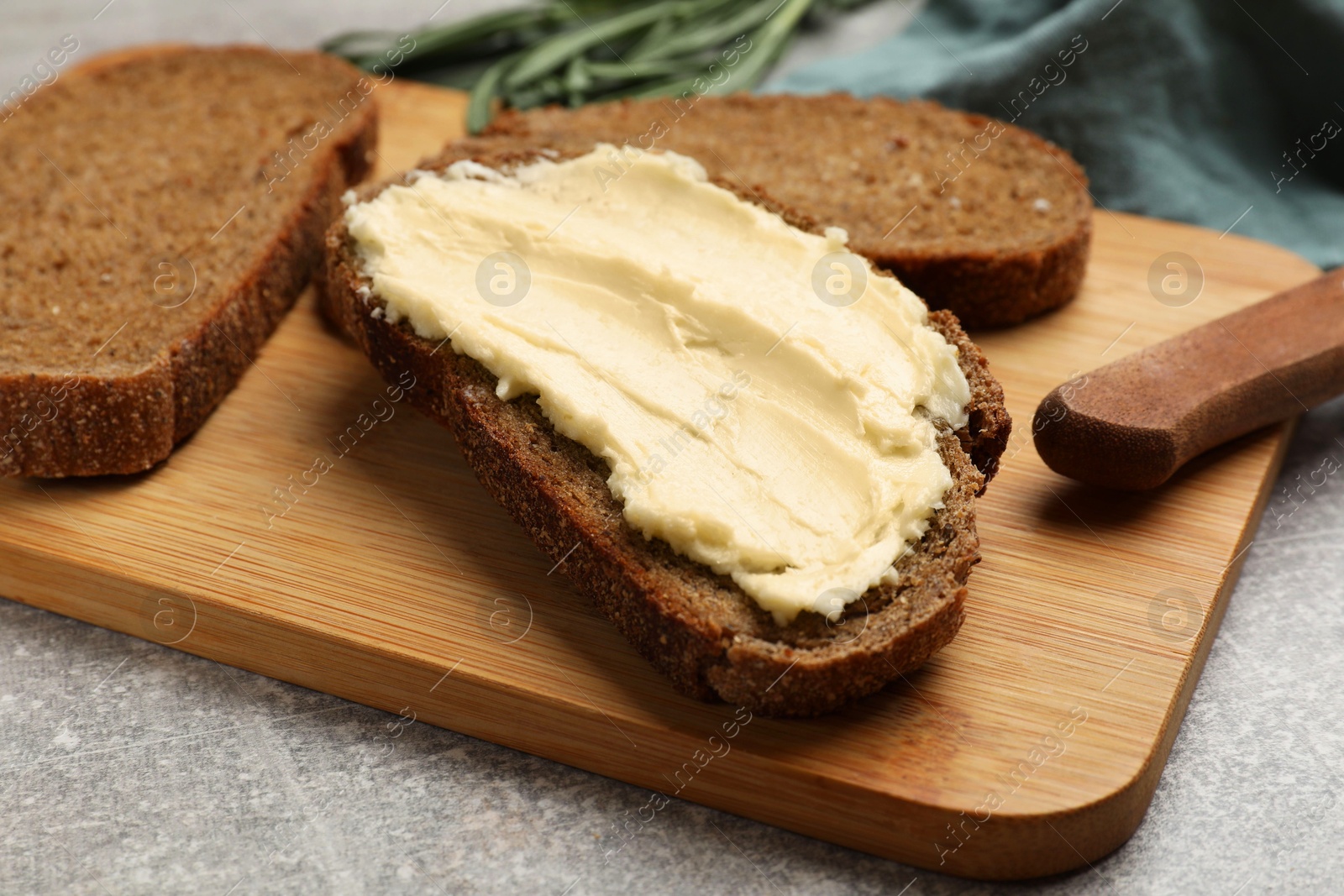 Photo of Fresh bread with butter and knife on grey table, closeup