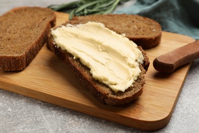 Photo of Fresh bread with butter and knife on grey table, closeup