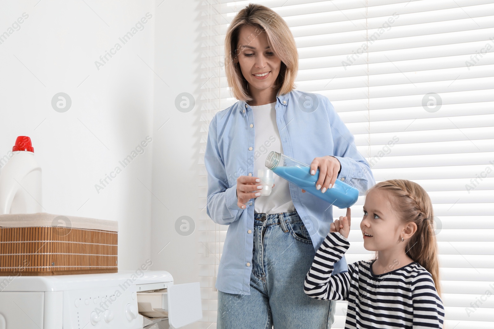 Photo of Little girl helping her mom doing laundry at home