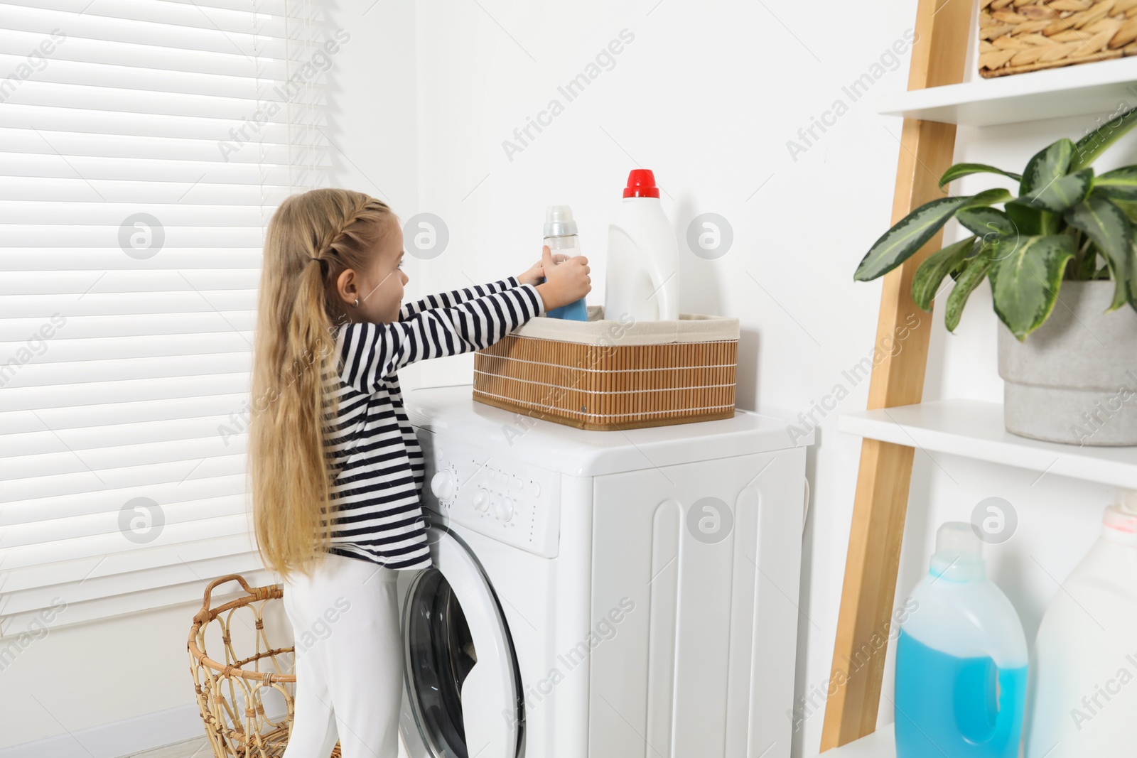 Photo of Little helper. Cute girl doing laundry at home