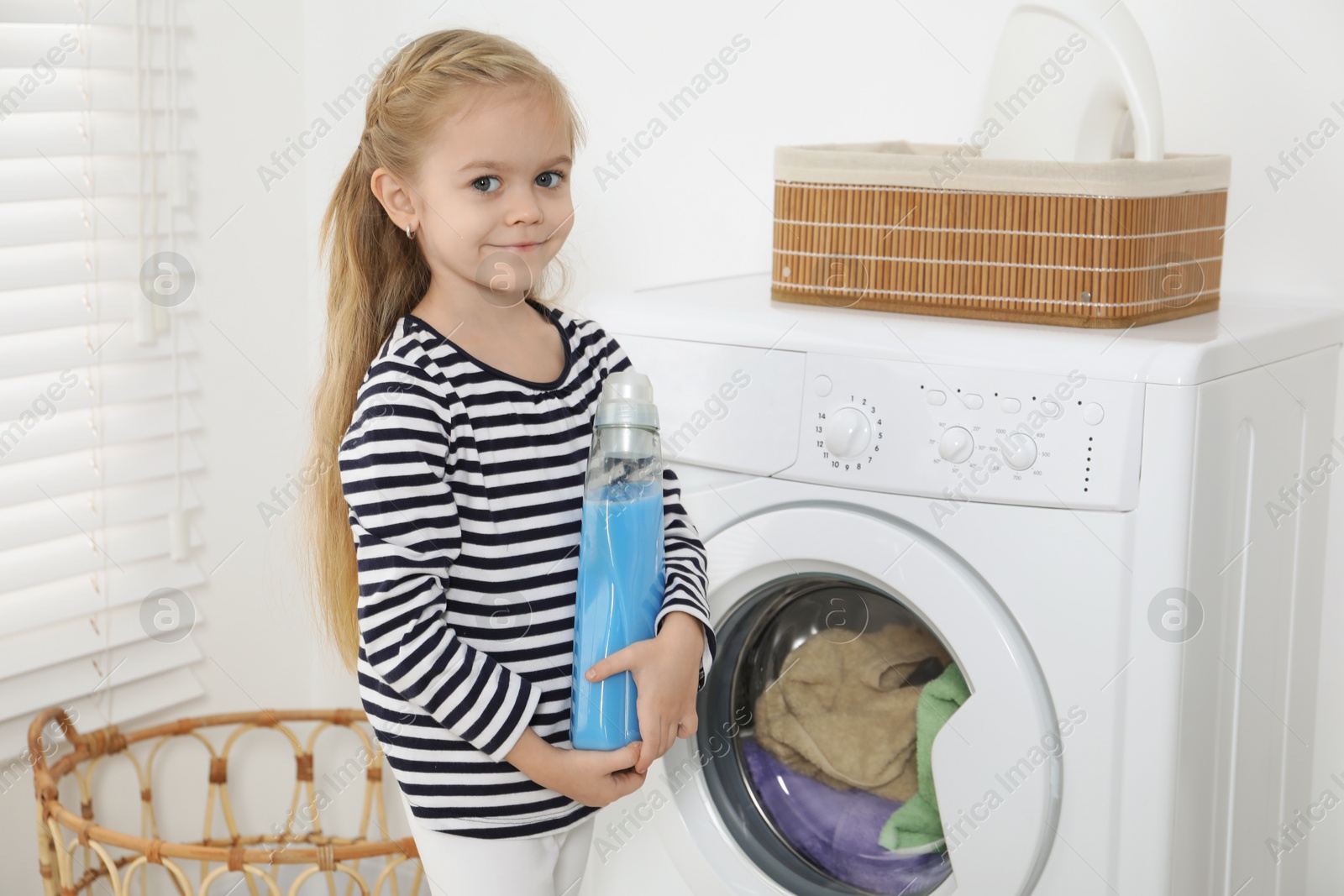 Photo of Little helper. Cute girl doing laundry at home