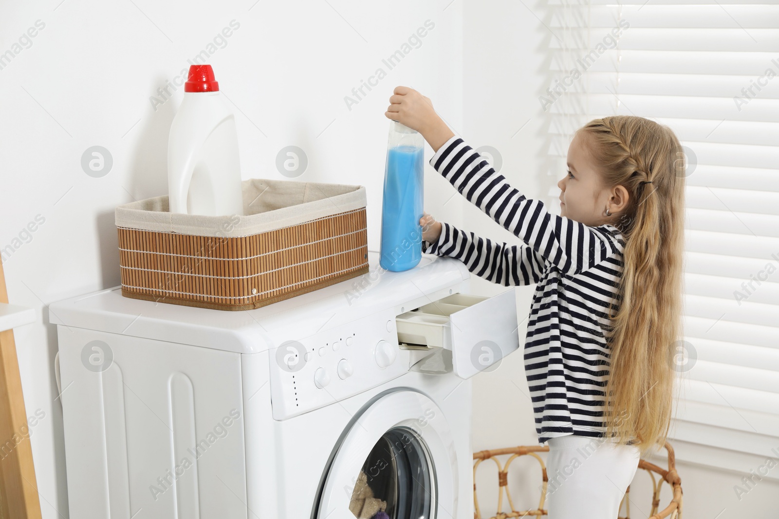 Photo of Little helper. Cute girl doing laundry at home