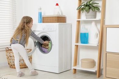 Little helper. Cute girl doing laundry at home, back view