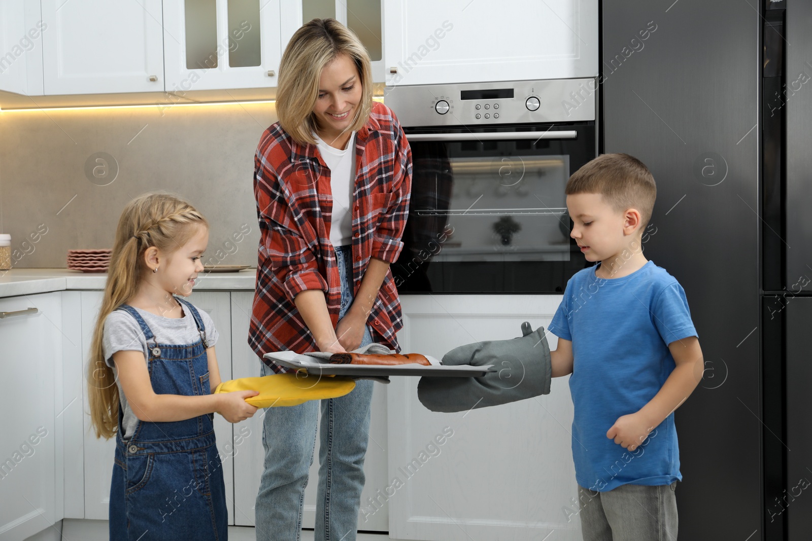 Photo of Little helpers. Children baking with their mother at home