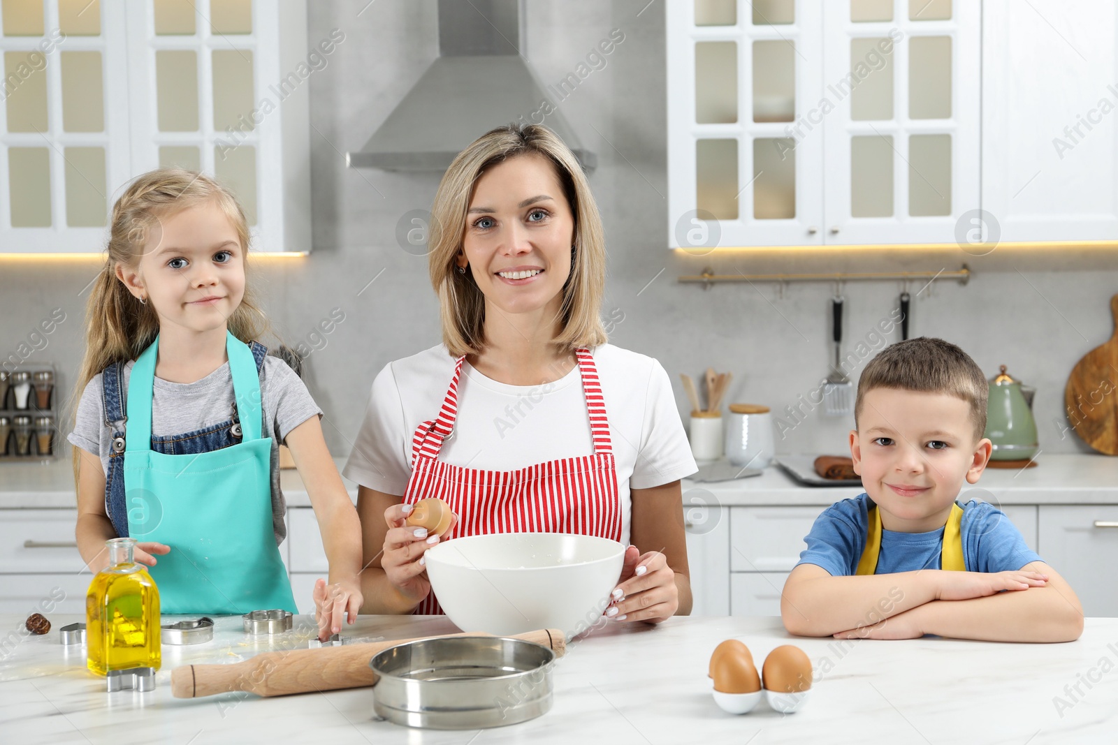 Photo of Children helping their mom making cookies in kitchen at home