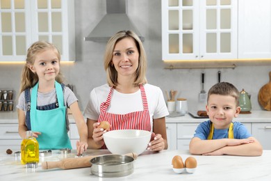 Children helping their mom making cookies in kitchen at home