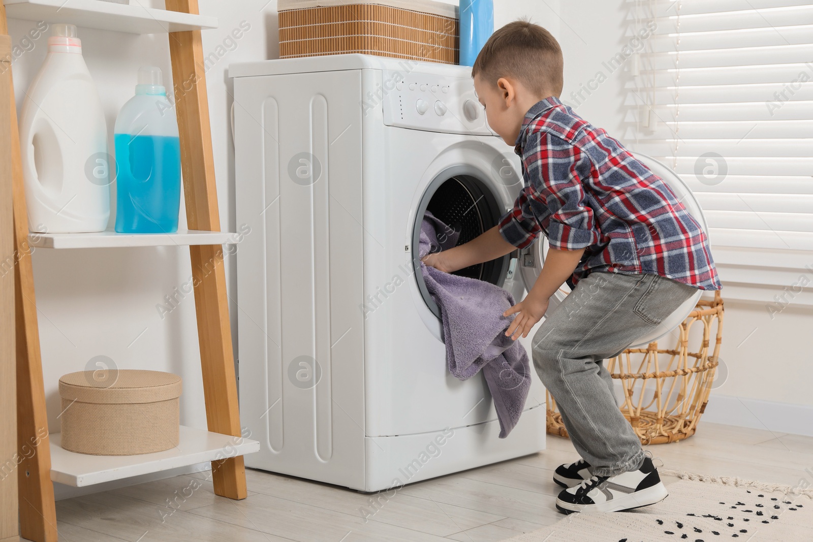 Photo of Little helper. Cute boy doing laundry at home