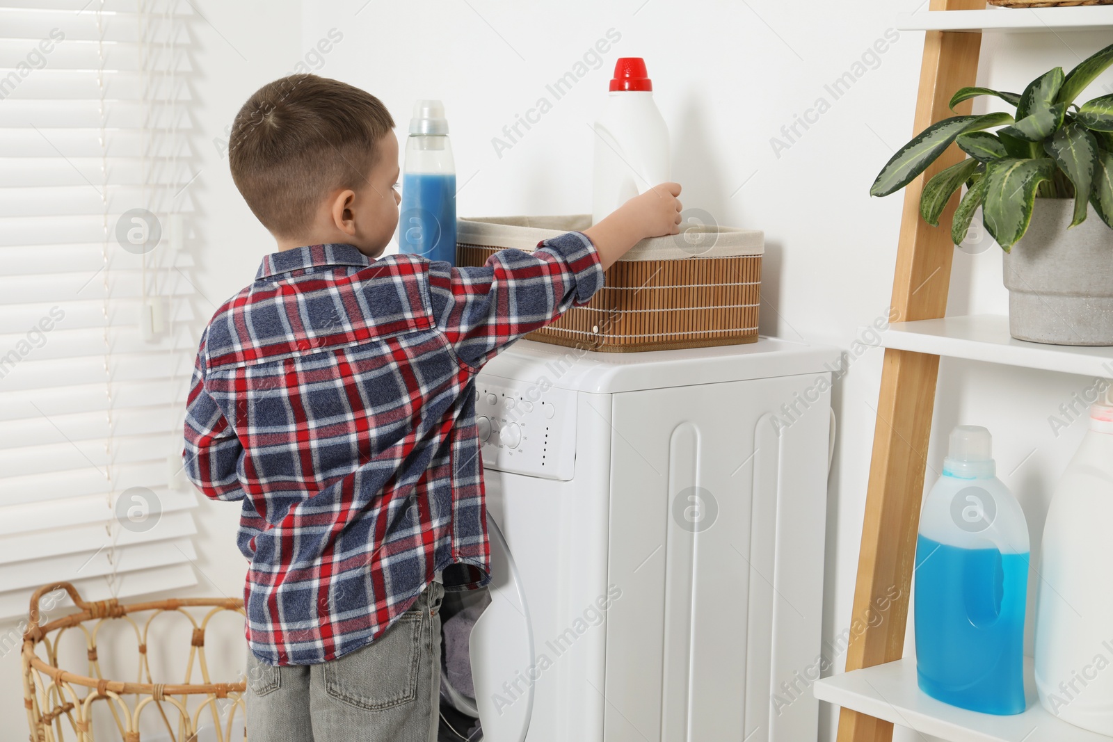 Photo of Little helper. Cute boy doing laundry at home