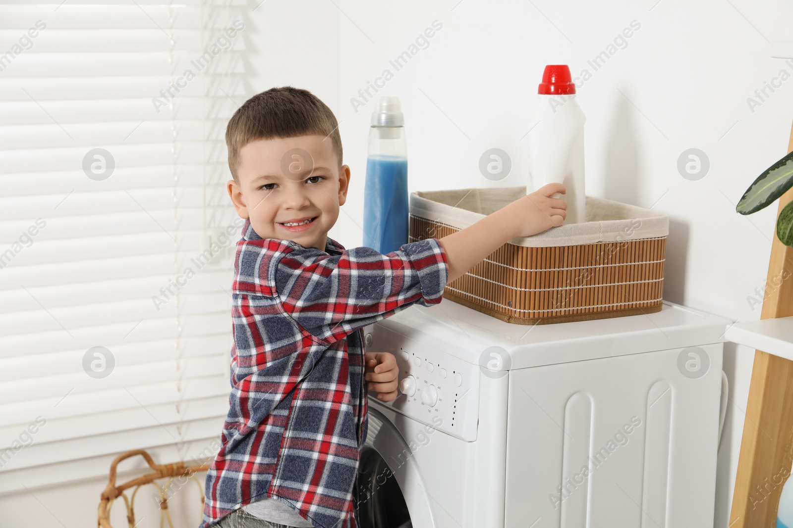 Photo of Little helper. Cute boy doing laundry at home