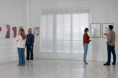 Photo of People studying beautiful art during event in gallery